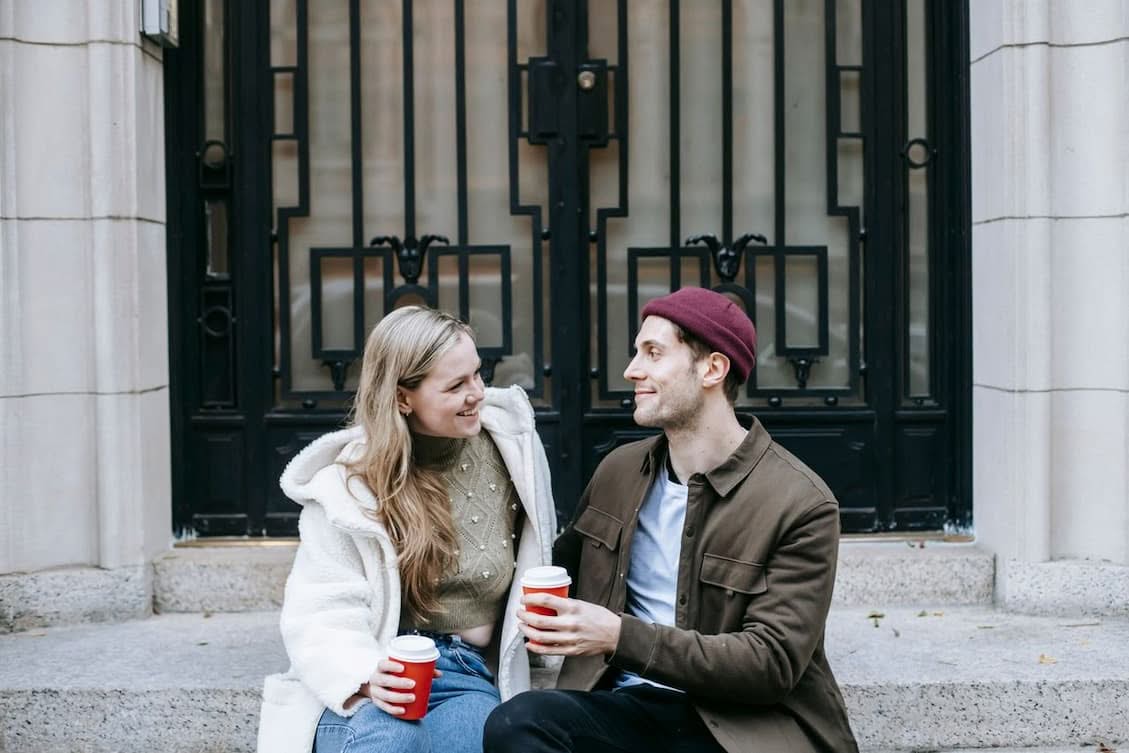 happy-man-and-woman-drinking-hot-tea-and-speaking-on-street